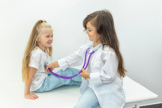 Two kids little girls playing doctor during a consult with a doctor in a medical office.