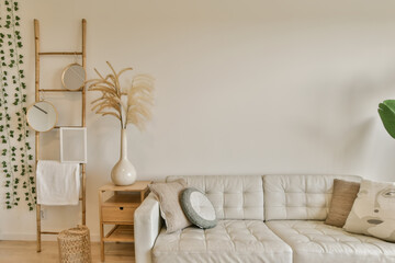 a living room with a white couch and some plants on the wall behind it is a wooden ladder that has been used for storage