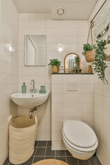 a small bathroom with a sink, toilet and plants in baskets on the wall next to the sink is a mirror