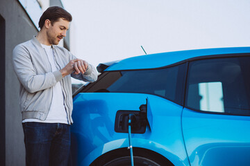 Man charging blue electric car