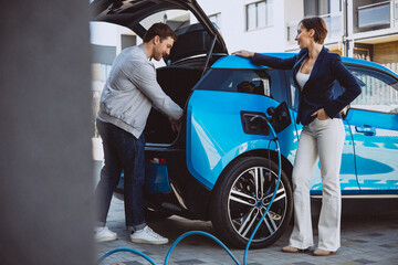 Couple talking by their electric car while its charging