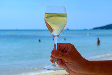 Summer time in Provence, glass of cold white wine on Pampelonne sandy beach near Saint-Tropez in sunny day, Var department, France