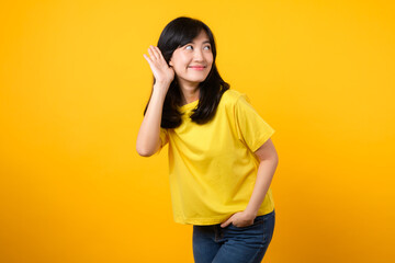 Capture attention portrait of young Asian woman. Wearing a yellow t-shirt and denim jeans, leans in...