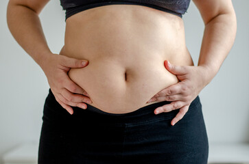 Overweighted woman squeezing belly seen from front
