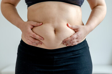Overweight woman squeezing her belly seen from front - obrazy, fototapety, plakaty
