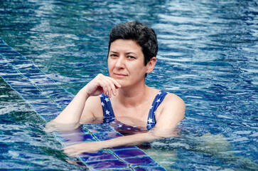 beautiful middle-aged woman with short black hair relaxes in the pool. A woman on vacation at spa