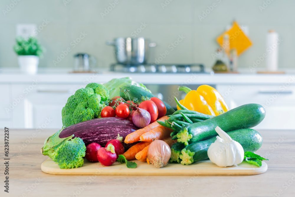 Wall mural Stylish modern kitchen with vegetables on the table. Bright white kitchen with homewares. The concept of a healthy lifestyle.