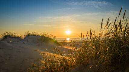 Weg zwischen den Dünen führt zum Strand bei Sonnenuntergang

