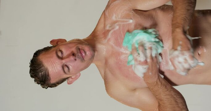 Athletic attractive fiteness caucasian male sportsman finishes his workout and comes to take a shower and wash away sweat and tiredness Slow motion Vertical view