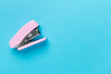 Pink stapler on color backgroung, top view