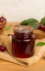 Jar with tasty homemade cherry jam on wooden table