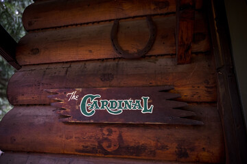 Sign that reads the cardinal hanging on log cabin