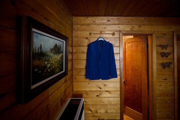 Fototapeta na wymiar Blue suit coat hanging on wooden cabin wall