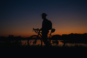 Silhouette of a man with a bicycle enjoying the sunset.