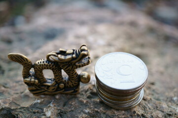 A Chinese dragon figurine and a stack of coins.
