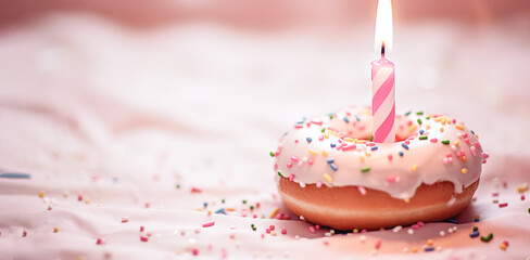 Pink donut and one burning candle against bokeh light background. Happy birthday concept.
