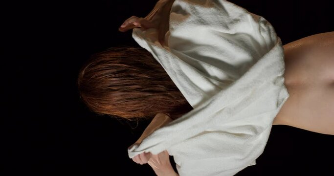 sexy slim redhead woman wipes her wet long hair with towel Daily routine in black bathroom isolated studio Slow motion vertical back rare view body and health care. softness