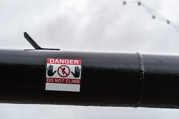Danger do not climb sign on the black gas pipeline, safety and infrastructure concept illustration.