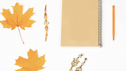 Autumn composition - notepad, women's jewelry, autumn leaves on a white background, flat lay, top view, copy space. Seasonal autumn concept.