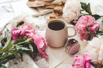 Cup of tea, macaroons and peonies, flat lay top view. good morning concept