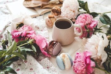 Cup of tea, macaroons and peonies, flat lay top view. good morning concept