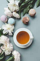Obraz na płótnie Canvas Cup of tea, macaroons and peonies, flat lay top view. good morning concept