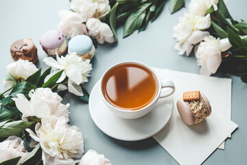 Cup of tea, macaroons and peonies, flat lay top view. good morning concept