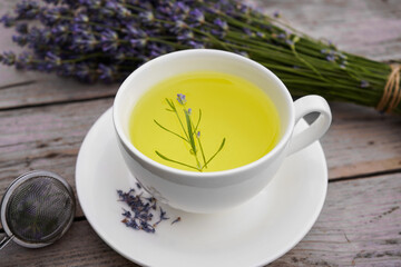 White cup with lavender tea and fresh lavender flowers on an old wooden background