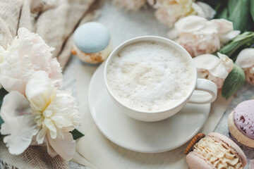 Obraz na płótnie Canvas Cup of coffee, sweet macaroons and white peonies, beautiful aesthetic photo