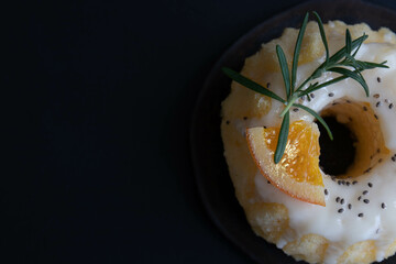 Orange bundt cake topped tangerines and rosemary on a white plate