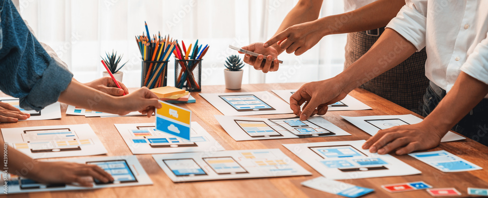 Poster Panorama shot of front-end developer team brainstorming UI and UX designs for mobile app on paper wireframe interface. User interface development team planning for user-friendly UI design. Scrutinize