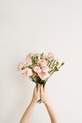 Female hands holding beautiful carnation flowers bouquet. Flat lay, top view. Elegant floral composition