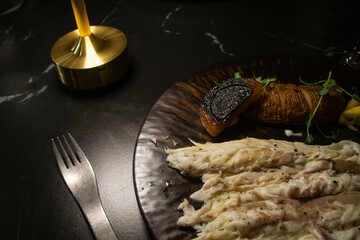 Sea Bass fish with fried hasselback potatoes on a brown plate in a restaurant