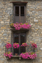 Fototapeta na wymiar Old stone house with beautiful flowers at the window in the medieval village of Ainsa in the pyrenees, Aragon, Spain