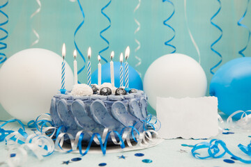 Blue birthday cake with candles and paper blank and celebration decoration