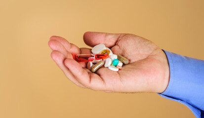 Man hand with different pills, capsules and ampoule. Immune system vitamins and supplemets. Man with pills in hand. Treatments and healthcare. Handful of variety medicine pills prescribed by doctor.