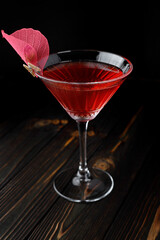 Red cocktail with rose decoration in a martini glass