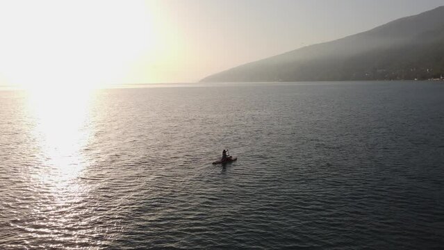 Girl is sailing on a sup board with a dog border collie and paddling along the sea along the Hawaiian islands with mountain and fog, on sunset