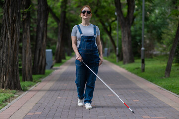 Blind pregnant woman walking in the park with a cane. 