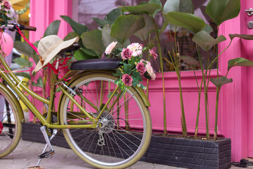 Fototapeta na wymiar Terrace of pink French-style cafe with a bicycle with a basket of pink flowers and balloon. Decor facade of coffeehouse with classic bike.