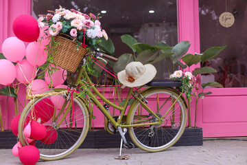 Fototapeta na wymiar Terrace of pink French-style cafe with a bicycle with a basket of pink flowers and balloon. Decor facade of coffeehouse with classic bike. 