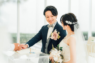 結婚式で結婚証明書・結婚誓約書にサイン・署名をする新郎新婦
