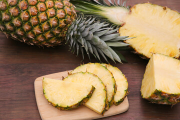 Cut and whole ripe pineapples on wooden table