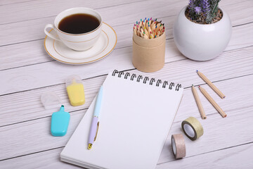 Open notebook, stationery and coffee on white wooden table. Planning concept