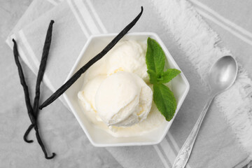 Delicious ice cream, mint, vanilla pods and spoon on light grey table, flat lay