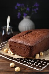 Delicious chocolate sponge cake and nuts on wooden table, closeup