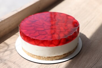 Delicious cheesecake with jelly and strawberries on wooden table, closeup