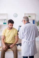 Obraz premium Young male patient visiting old male doctor
