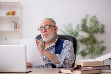 Old male writer sitting at workplace