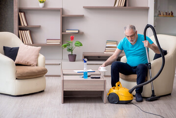 Old male contractor cleaning the house